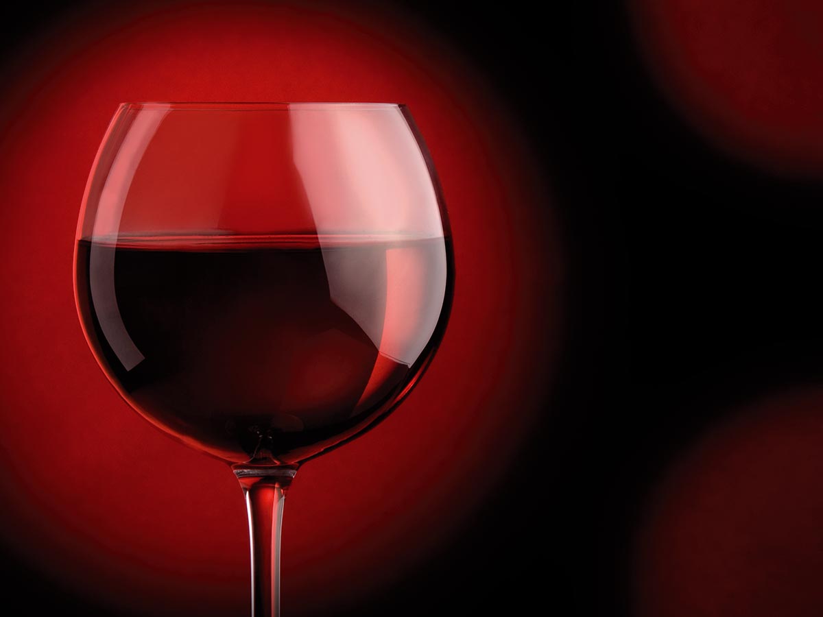 Rotweinglas-weinseminar-berlin Glas Rotwein vor rotem Hintergrund